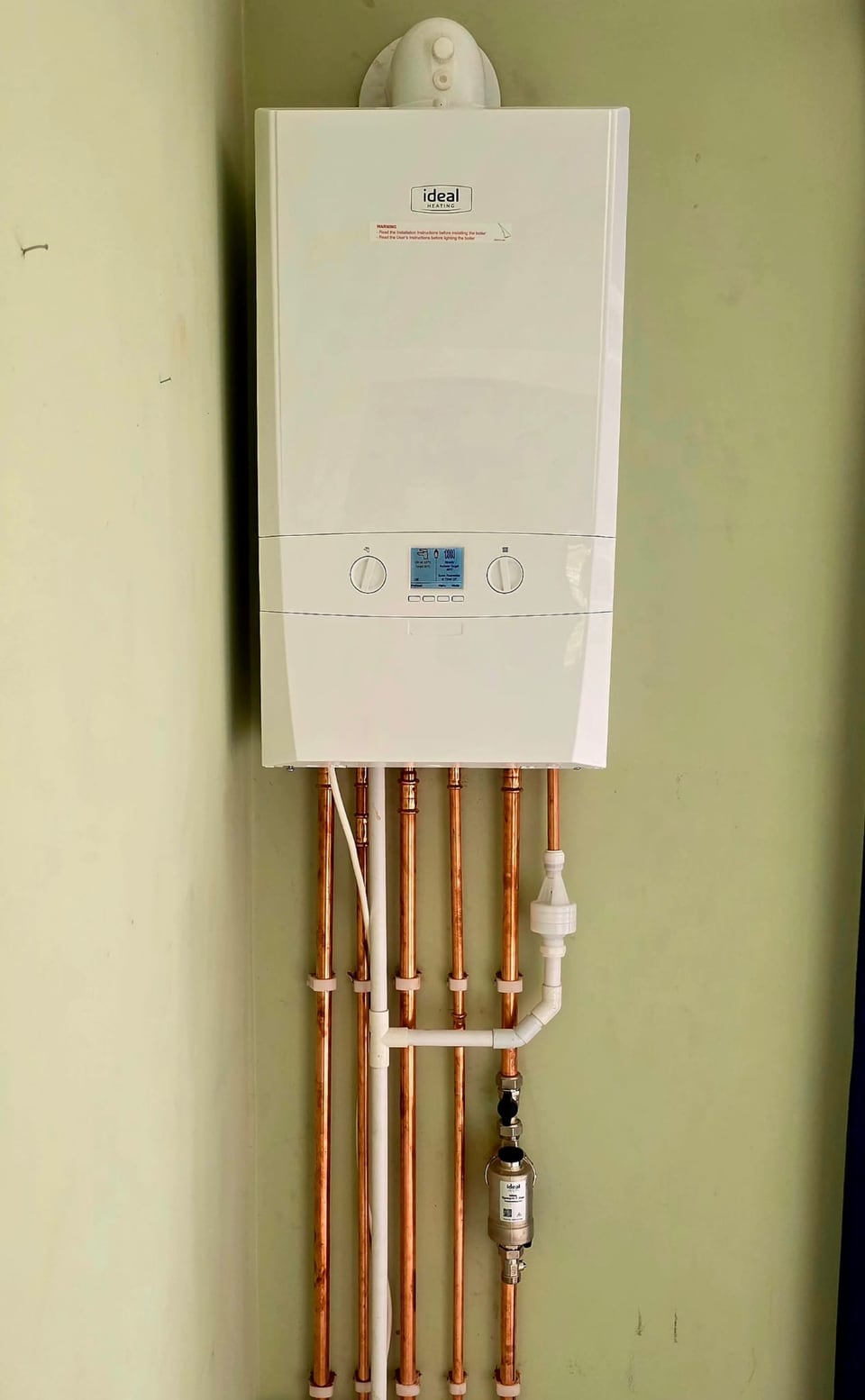 Wall-mounted Ideal boiler with exposed copper pipework and filter