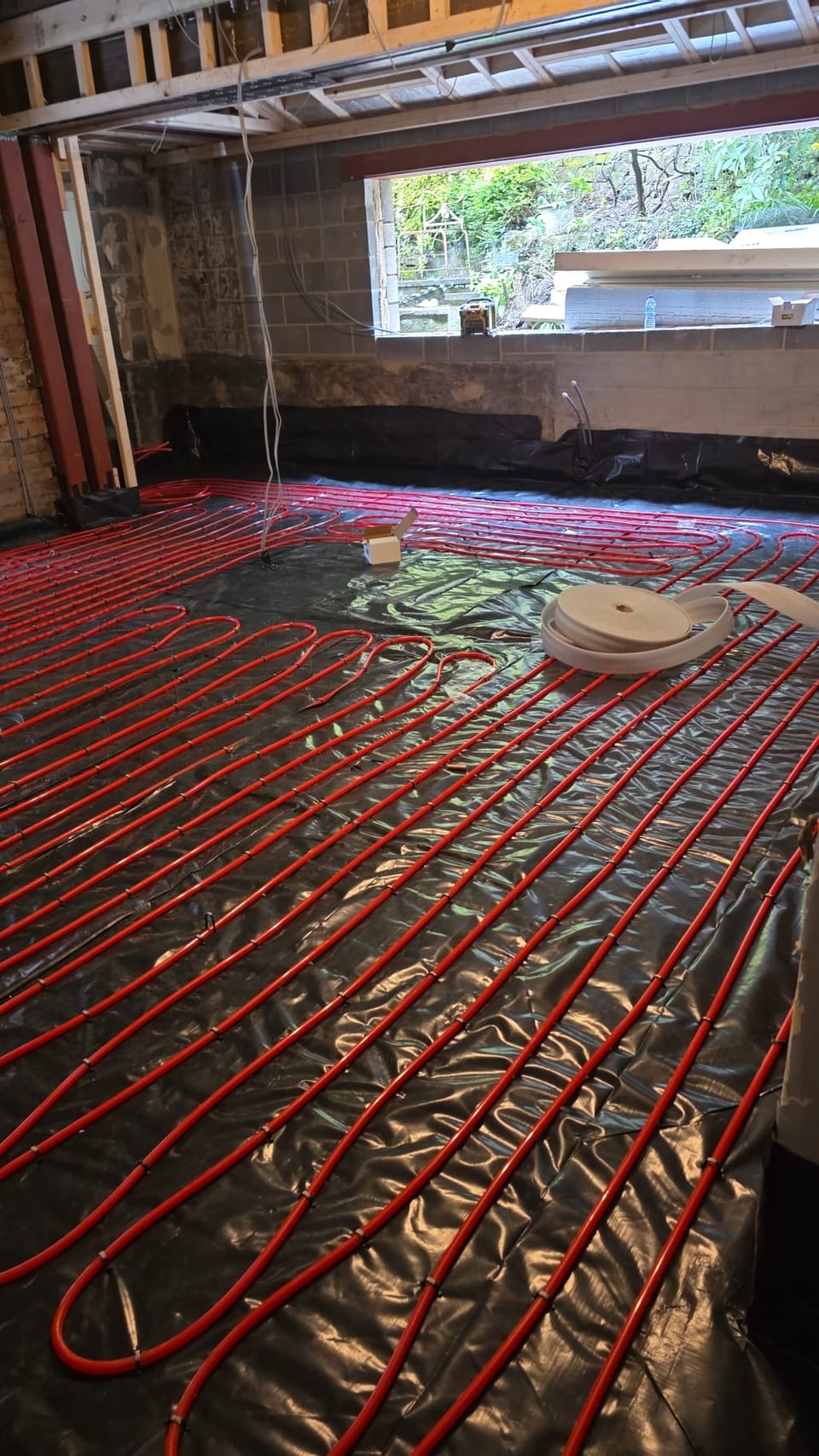 Red underfloor heating pipework laid across a renovation floor
