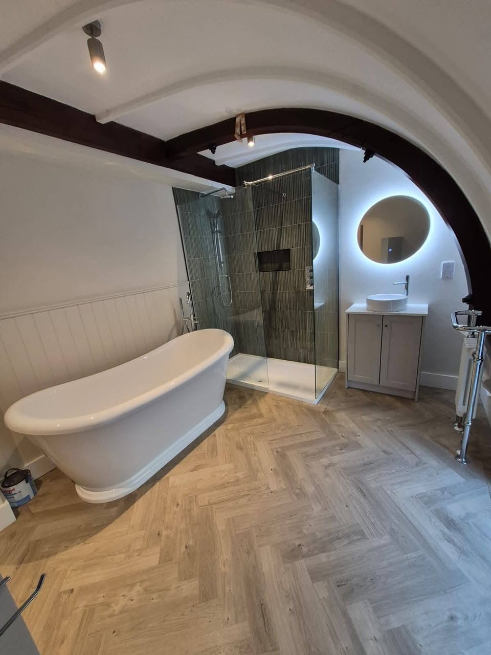 Bathroom with a white freestanding bath, glass shower, vanity basin and round illuminated mirror